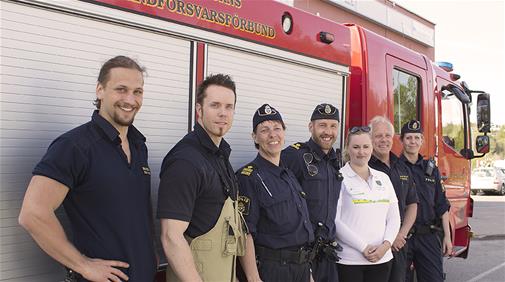 Gruppbild framför en brandbil på brandmän, poliser och säkerhetssamordnare.